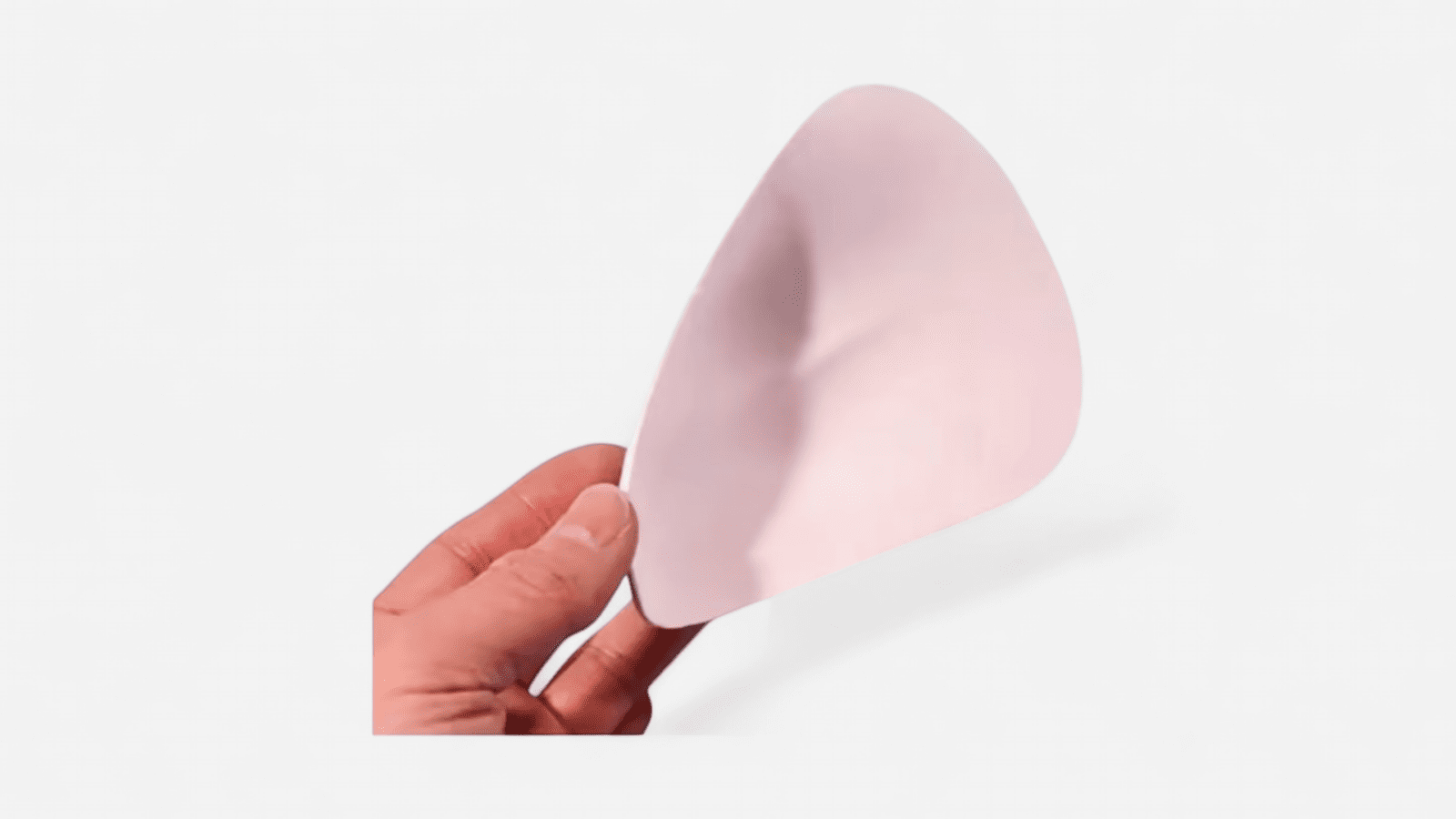 Bézs gaffszivacsbetét kézben tartva oldalnézetből, diszkrét tuckinghoz és sima sziluetthez – Szexshop Belváros. Beige gaff foam insert held in hand from side view for discreet tucking and smooth silhouette – Szexshop Belváros.