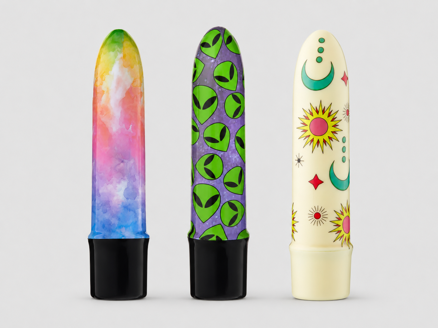 HU: Mini Máz minivibrátor három különböző dizájnban – Színorgia, Idegen Behatoló és Égi Csábító egymás mellett, világosszürke háttéren. EN: Mini Máz mini vibrator in three different designs – Színorgia, Idegen Behatoló, and Égi Csábító shown side by side on a light grey background.