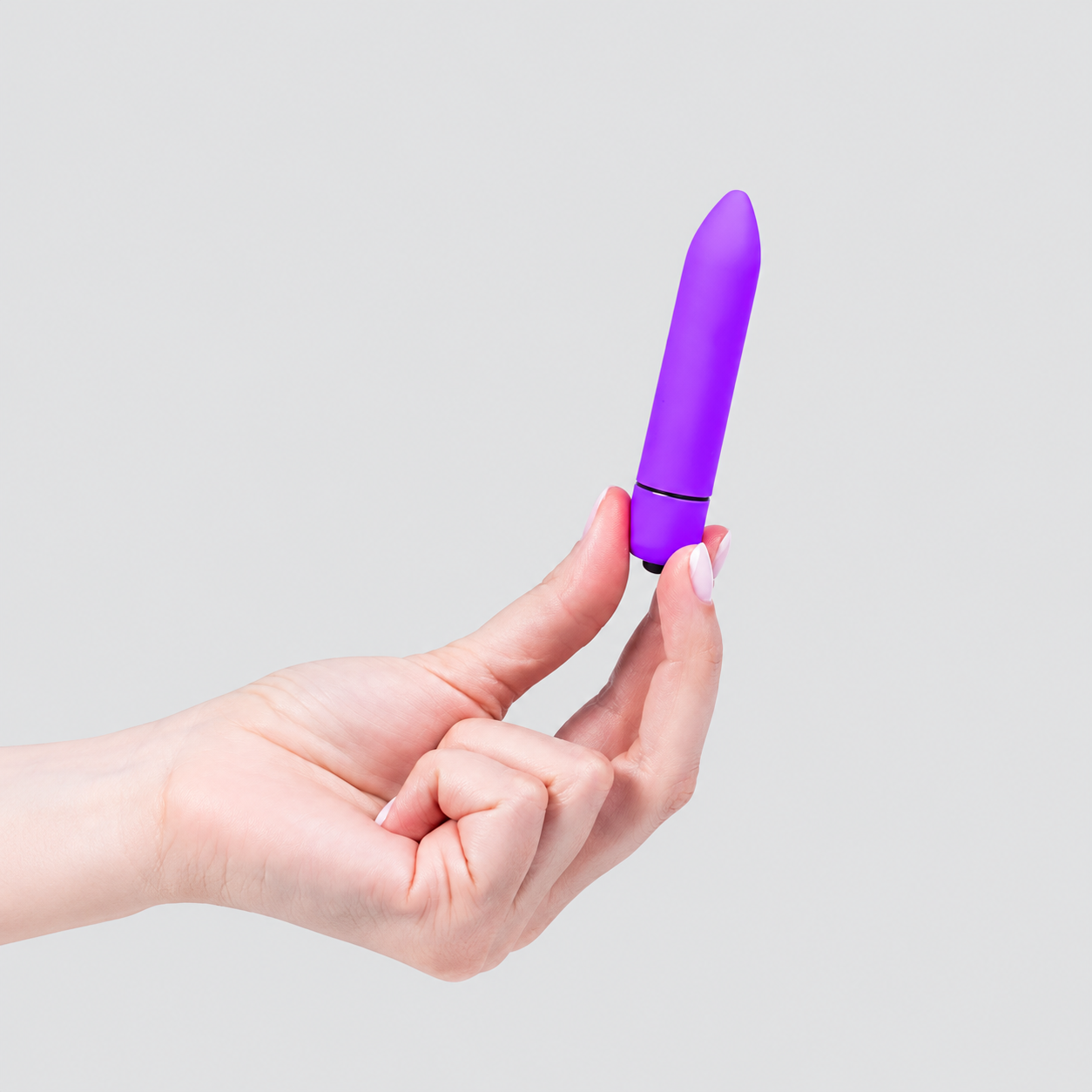 HU: Lila Lövedék mini vibråtor kézben tartva, a kompakt méret bemutatåsåra. EN: Purple Bullet mini vibrator held between fingers to show its compact size.