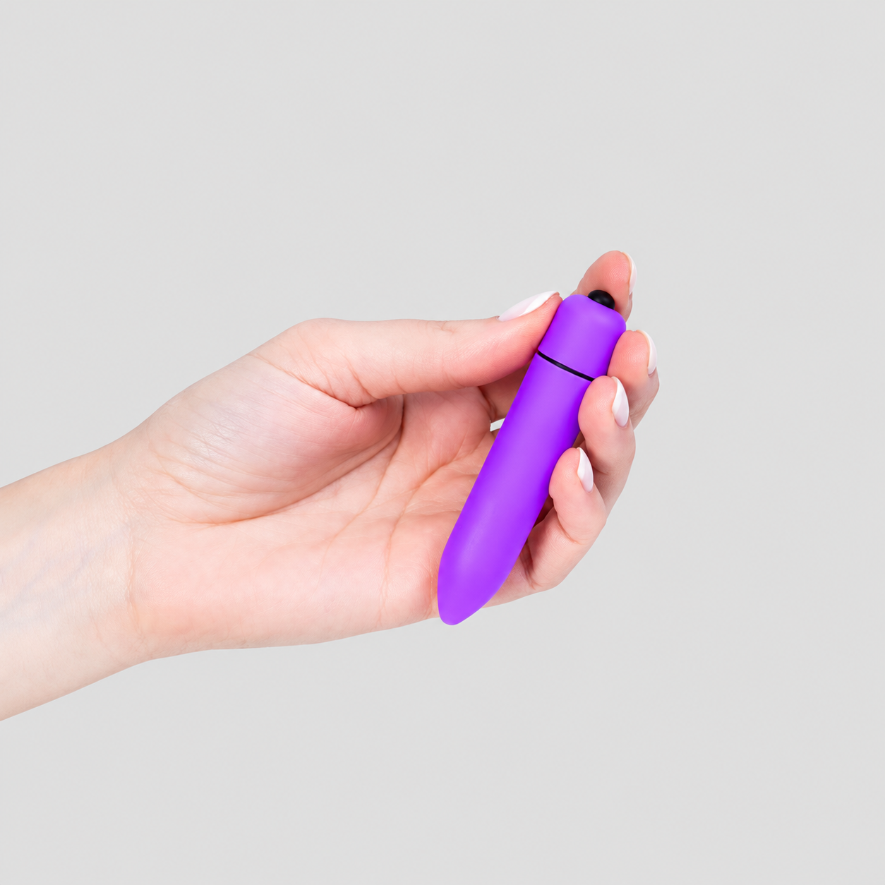 HU: Lila LövedĂ©k mini vibrĂĄtor kĂ©zben tartva, fekete vezĂ©rlĆgombbal Ă©s lila ABS testtel. EN: Purple Bullet mini vibrator held in hand, showing the black control button and purple ABS body.